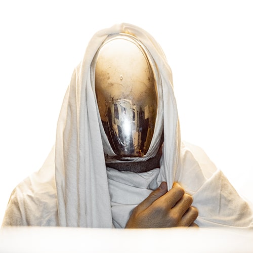Photo of a faceless character figure with a reflective mask/helmet in a white robe  - Alex Iby on Unsplash