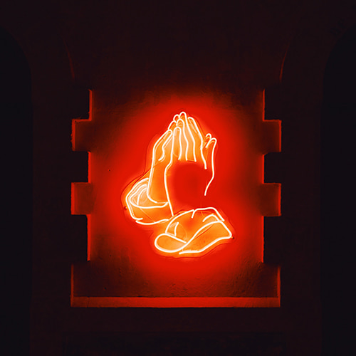Image of neon lights in the shape of hands praying in a recessed wall  - George Kedenburg III on Unsplash