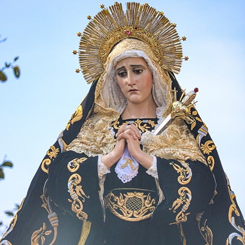 Photo of a Virgin Mary statue in an ornately decorated cloak and head piece  - Lisandro Garcia on Unsplash