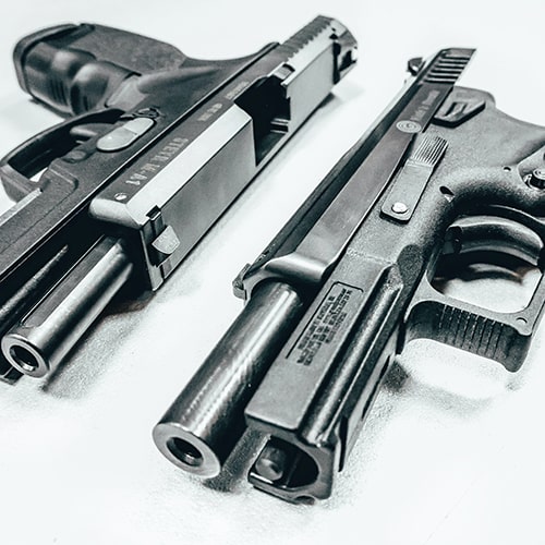 Close-up shot of two pistols set on a white surface - Maxim Potkin on Unsplash