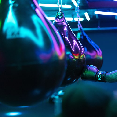 Photo of three punching bags, one being hit by a boxing glove - ThisisEngineering RAEng on Unsplash