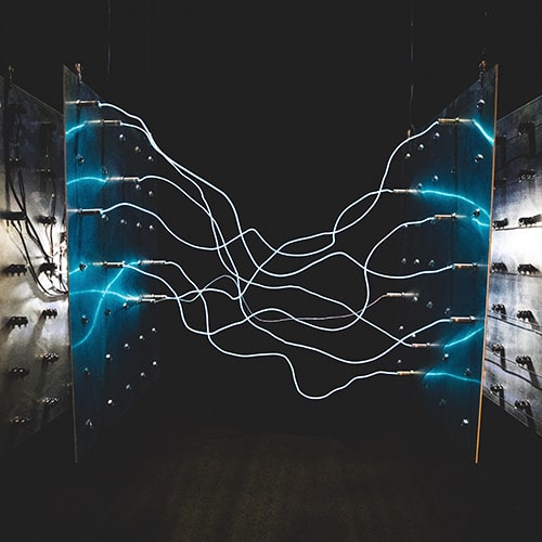 Photo of two square blue LED light panels with electrical cables connected between the two | Wonderspaces exhibit in San Diego - israel palacio on Unsplash