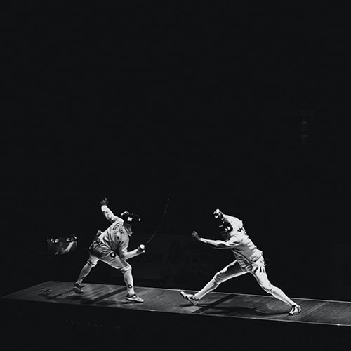 Black and white image of two fencers competing in a competition match