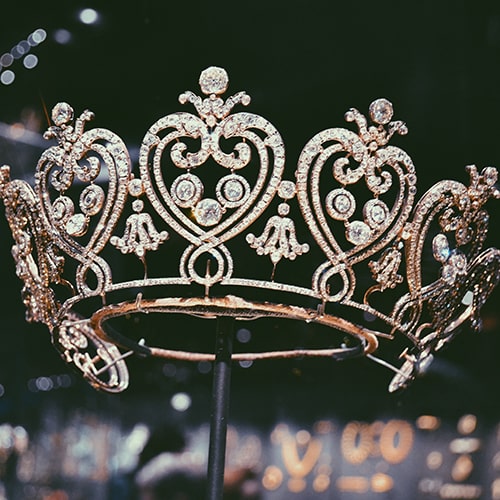 Photo of a crown/tiara with heart-shaped segments on a stand in a glass display case - Amy-Leigh Barnard on Unsplash