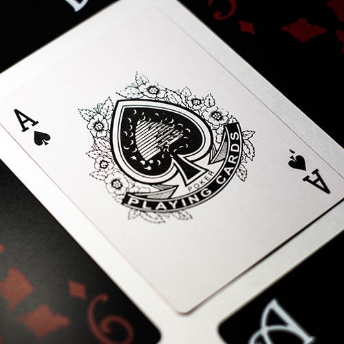 Black and white close-up of a hand, splatterd with some kind of dark liquid (possibly ink) holding a lit match.