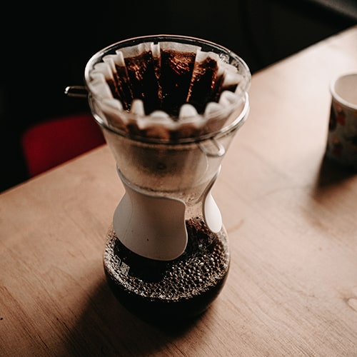 Hand-filtered and -brewed coffee draining into a bulb-shaped receptacle.