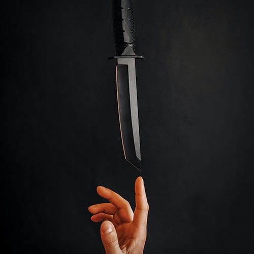A dagger floating tip-down above an someone's hand.