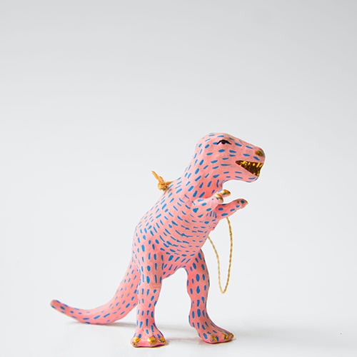 Photo of a pink dinosaur figurine with blue dashed line 'markings' and a gold chain loop on its back - Miguel Andrade on Unsplash