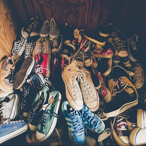Collection of a plethora of Converse sneakers in a wooden wall inlet - Jakob Owens on Unsplash
