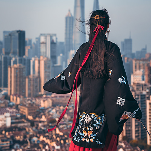 Photo of a woman dressed in a kimono staring out over a cityscape - 丁亦然 on Unsplash