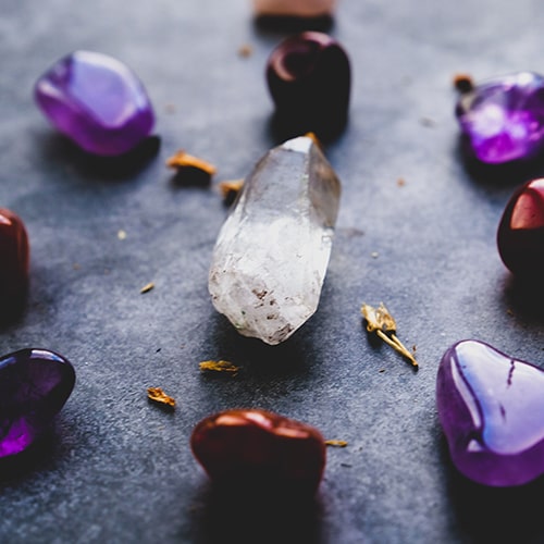 Photo of purple gemstones surrounding a white obelisk crystal - Dan Farrell on Unsplash