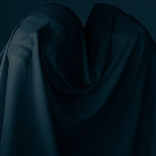 Dark photo of two figures cloaked in a semi-sheer cloth - Katsiaryna Endruszkiewicz on Unsplash