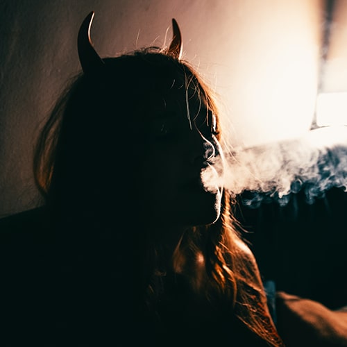 Side-lit imge of a woman with horns blowing smoke - Stefano Ciociola on Unsplash