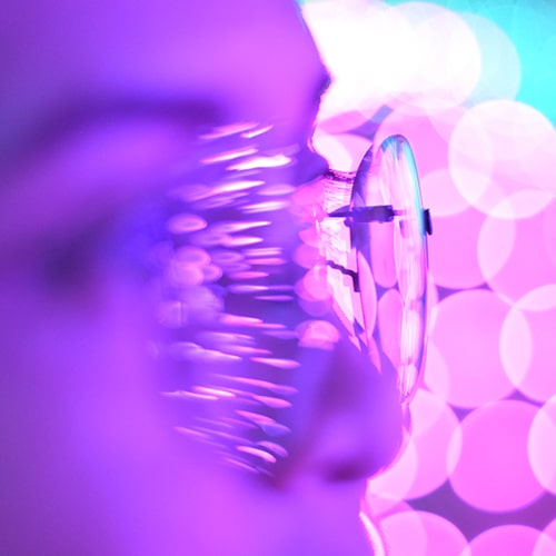 Abstract photo of a person wearing glasses with bokeh light effects in the background and foreground