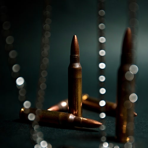 Focused shot of bullets with beads/chains blurred and unfocused in the foreground - Michael Surazhsky on Unsplash