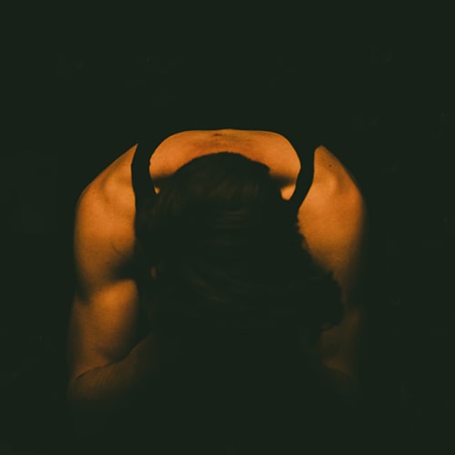 Photo of a man in a tanktop beant over, his hands on or over his face - lucas clarysse on Unsplash