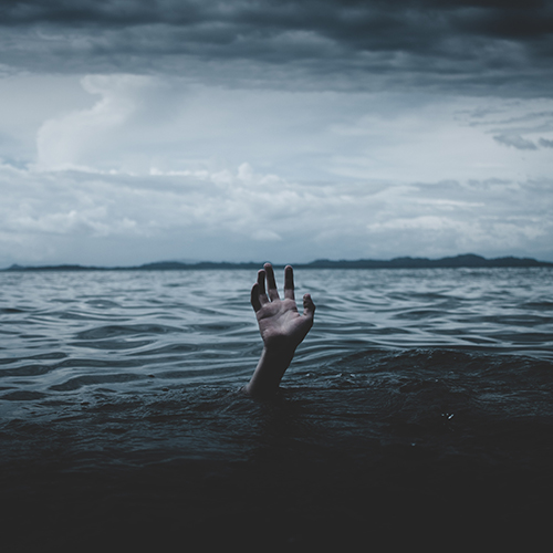 Photo of a dark, brooding ocean environment with storm clouds and a hand reaching up out of the water