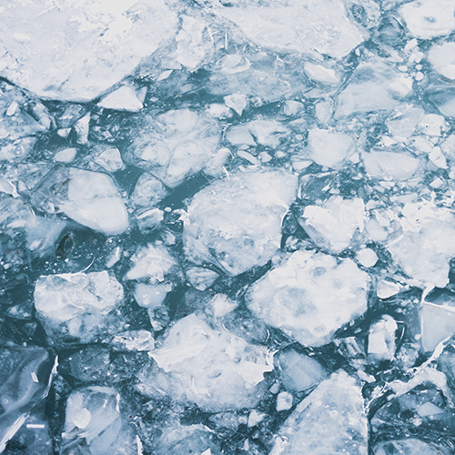 Photo of a broken ice shelf/layer floating on teal blue water - Bryan Rodriguez on Unsplash